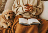 Person holding a mug with a puppy and an open book on a blanket. Size - 100cm x 70cm